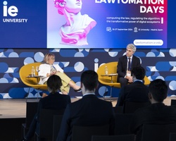 A woman speaks at a podium during a panel discussion at the Lawtomation Days event, with other panelists and an audience in attendance.
