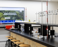 A modern laboratory with various scientific equipment and a digital display promoting environmental sciences.