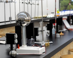 A modern laboratory setup featuring a voltage generator and various scientific instruments on a countertop.