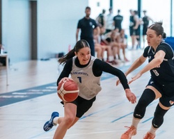 Two female basketball players are competing in a game.