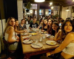 A group of eight young women sitting around a dining table in a lively restaurant.