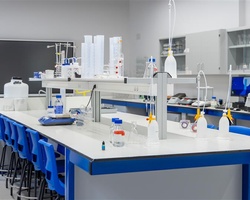 A modern laboratory workspace with various equipment on countertops and blue chairs.