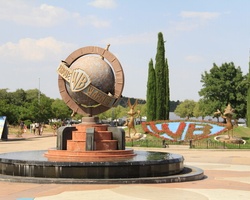 A large globe with the Warner Bros logo is located in a park setting.
