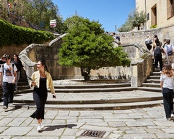 A group of people walking through a stone pathway with a small tree in the center.