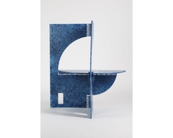 A geometrically shaped blue sculpture that stands vertically, featuring circular and rectangular cut-outs.
