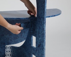 A child's hands touching a blue felt-covered chair