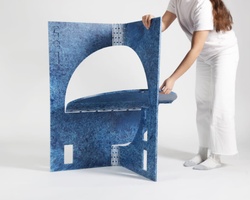 A person is setting up a blue, abstract foldable display panel on a white background.