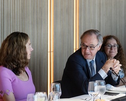 A group of people engaged in conversation at a dining table in a modern setting.
