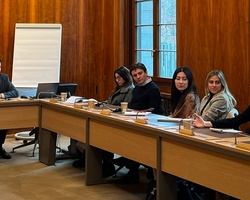 A group of people engaged in a meeting around a conference table.