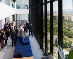 Business professionals gathered on a modern office building balcony overlooking a cityscape.