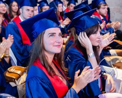 A group of graduates in blue caps and gowns celebrating during a ceremony.