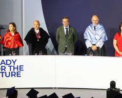 A group of professionals in formal attire standing behind a podium with a backdrop that reads 'READY FOR THE FUTURE'.