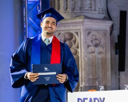 A graduate proudly holding their diploma during a ceremony.