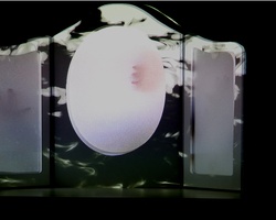A mysterious object with a glowing central orb flanked by two translucent panels against a dark background