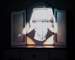 A person's face illuminated by a glowing screen in a dark room, creating a dramatic effect.