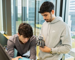 Two young men are collaborating on a robotics project in a modern office environment.