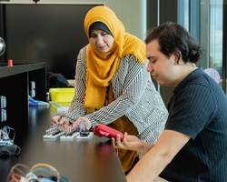 Two individuals are working together on electronic components in a modern workspace.