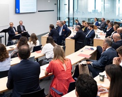 A diverse group of professionals are attending a seminar in a modern conference room.