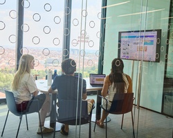 A group of three people collaborating in a modern conference room with a view.