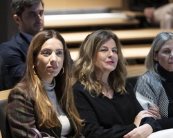 A group of people, mostly women, sitting in a conference room attentively listening.