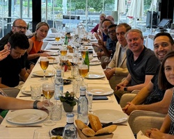 A group of people sitting at a long dining table in a restaurant, smiling at the camera.