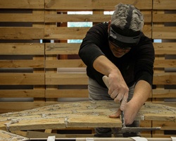 A man is sculpting a stone piece while wearing augmented reality glasses.
