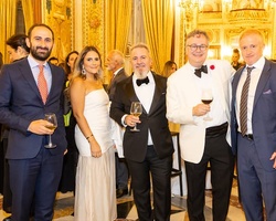 A group of five elegantly dressed people posing together at a formal event.