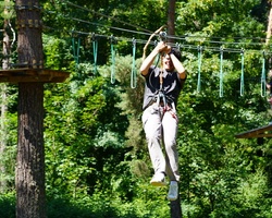 A person is enjoying a zip line adventure in a lush green forest.