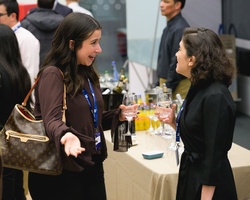 Two women are engaged in a lively conversation at a social event with drinks around.