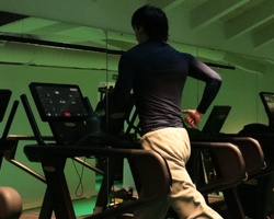 A person running on a treadmill in a gym setting.