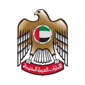 This is an emblem featuring a falcon with outstretched wings, holding a disc with the flag of the UAE, surrounded by Arabic text.