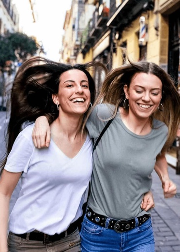 Two joyful women walking and laughing together on a city street