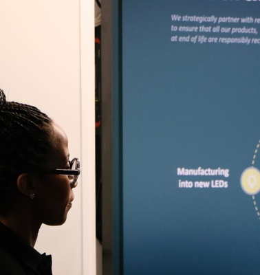 A person is observing an informational display about a circular model for recycling LED products.