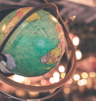 A vintage globe in a metal frame with soft glowing lights in the background.