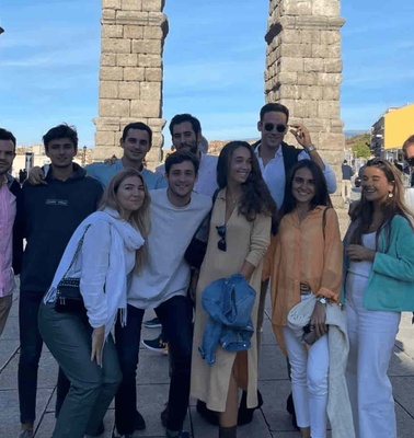 A group of young adults smiling in front of an ancient Roman aqueduct.