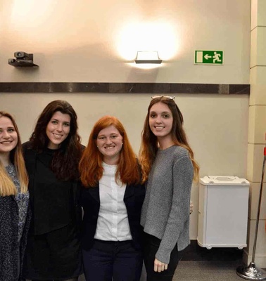 Four women smiling inside a room with flags of Spain and the European Union in the background.