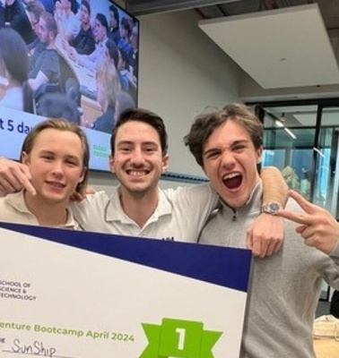 Three young men smiling and posing together with a certificate at a tech event.