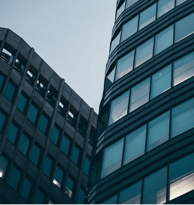 Low angle view of two modern skyscrapers against a twilight sky.