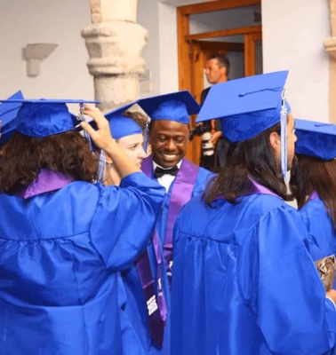 A group of graduates in blue gowns and caps celebrating during a graduation ceremony.