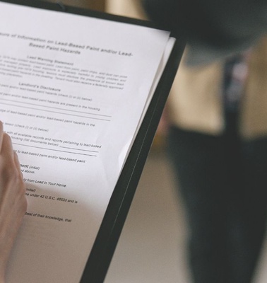 A person is filling out a form while others are blurred in the background.