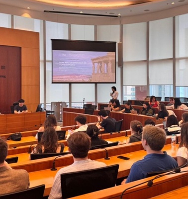 A presentation is taking place in a university auditorium with students attentively listening.