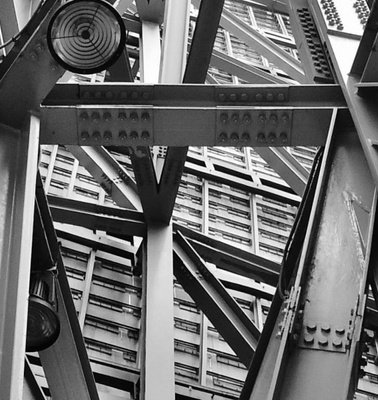 A black and white photo of an intricate steel structure of a building from a low angle view.