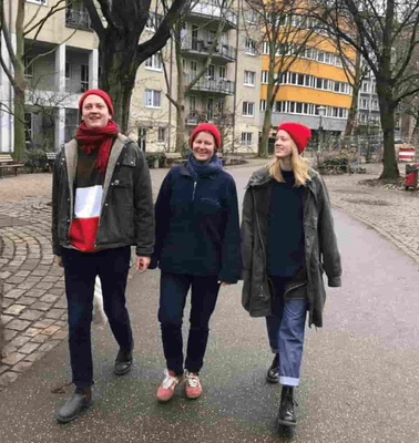 Three people walking happily in an urban park during winter.
