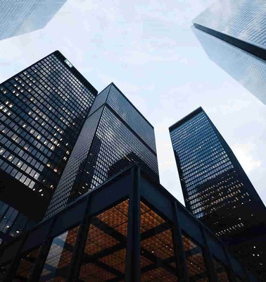 Low-angle view of several skyscrapers against a dusky sky, highlighted by the building lights.