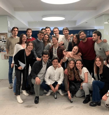 A group of young adults smiling and posing for a photo in a modern indoor setting.