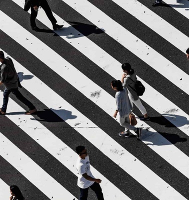 People crossing a large zebra crossing in an urban area