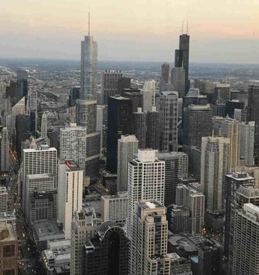 Aerial view of a dense urban cityscape with numerous high-rise buildings at dusk.