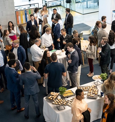A large group of people mingling at a networking event with food and drinks.