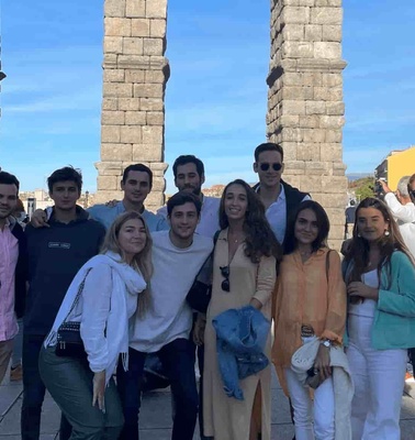 A group of young adults posing for a photo in front of an ancient aqueduct.