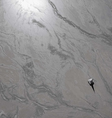 Aerial view of a single person walking on a textured, icy surface, creating a solitary impression.